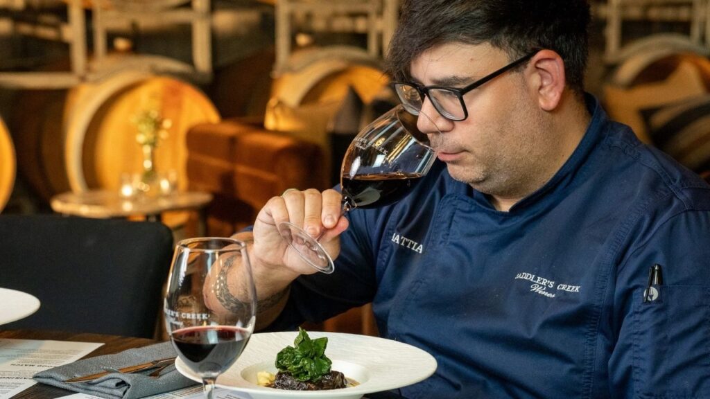 Chef Chiero tasting red wine beside a lamb course